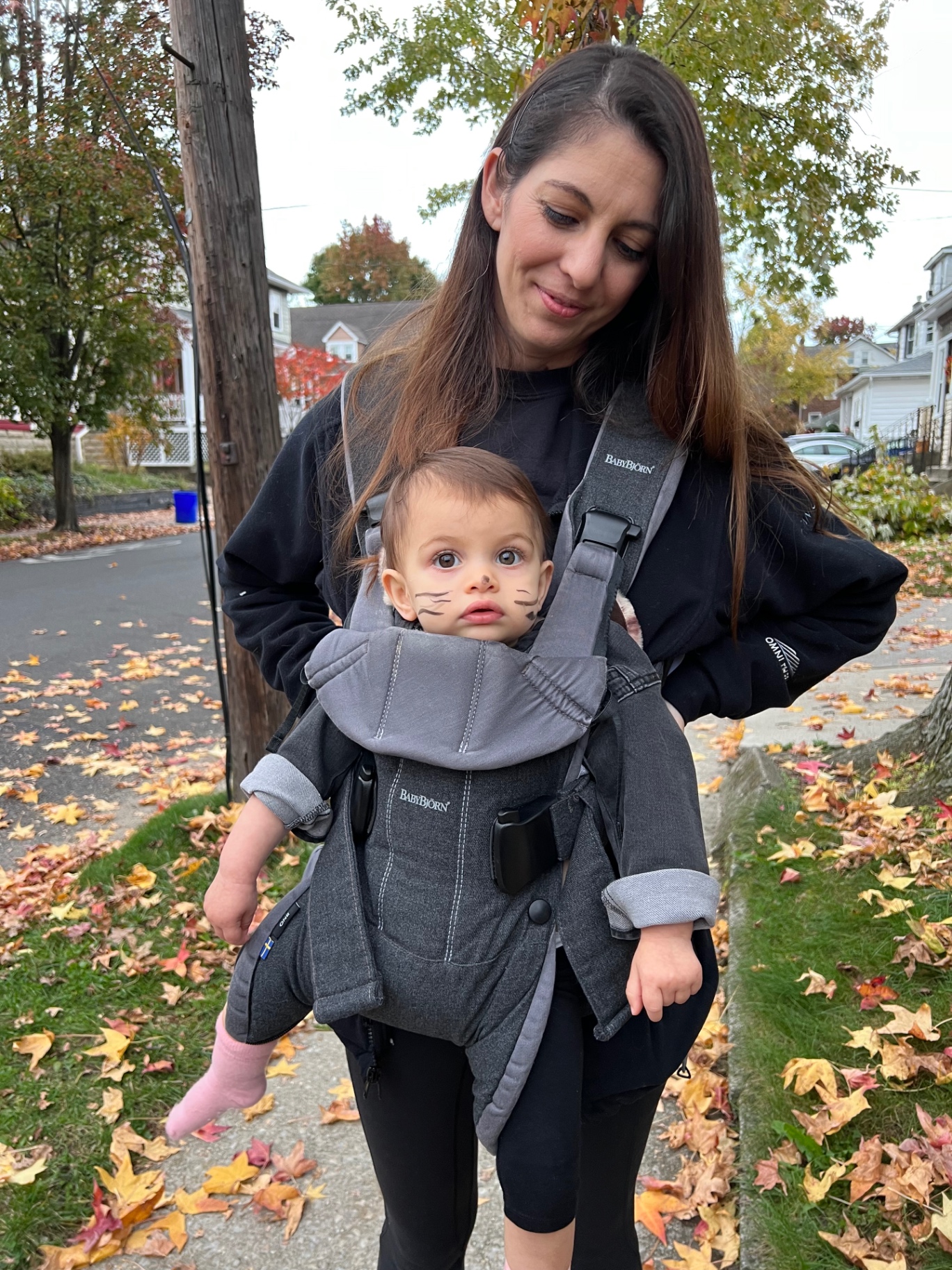 The mom behind Comfy Kids Co holding her toddler outside on an autumn afternoon